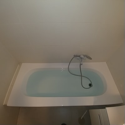 אמבטיה עם מים וברז מקלחת על קיר אריחים