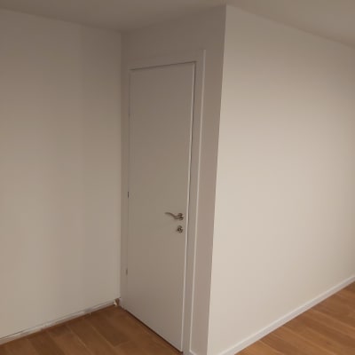 קיר גבס עם דלת לבנה ורצפת עץ