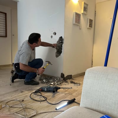 אדם עובד עם פטיש על קיר שבור