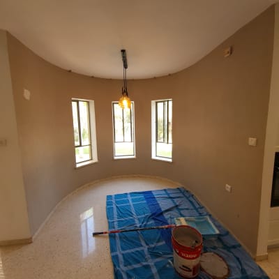 חדר עם קירות צבועים, דלי צבע ומברשת על יריעה