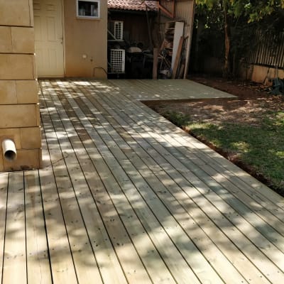 דק עץ חדש בגינה ליד דשא ירוק