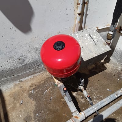 מיכל לחץ אדום וצינורות מתכת עם ברזים