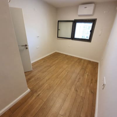 רצפת פרקט עץ בחדר ריק עם קירות לבנים