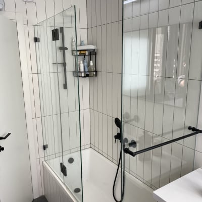 מקלחון זכוכית עם ברזים שחורים בחדר אמבטיה