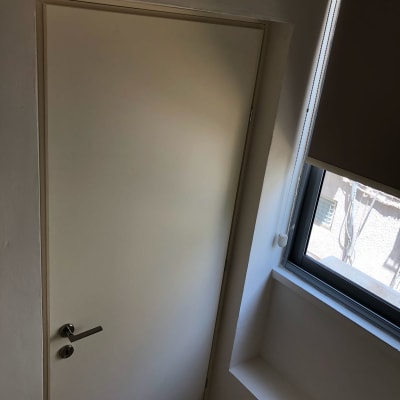 דלת לבנה עם ידית מתכת ליד חלון