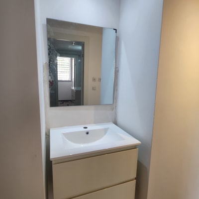 כיור לבן עם מראה מותקנת על הקיר