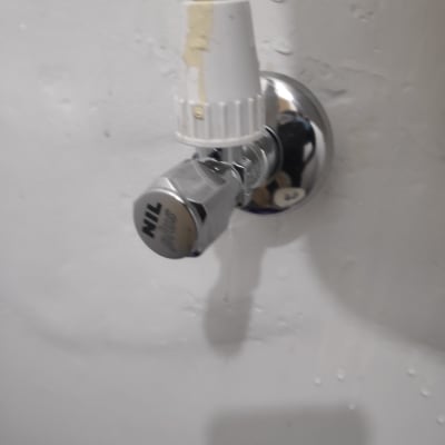 ברז מים עם צינור מחובר לקיר לבן