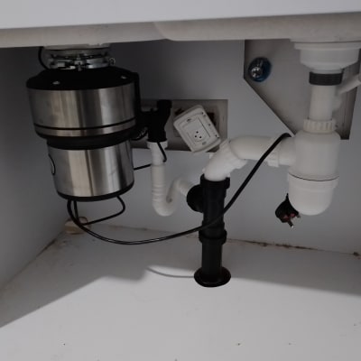 צנרת מתחת לכיור עם טוחן אשפה ומחברים