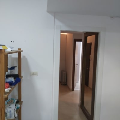 קיר גבס לבן עם מתג חשמל ליד מדף עץ