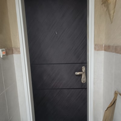 דלת שחורה עם ידית מתכת כסופה במסגרת לבנה