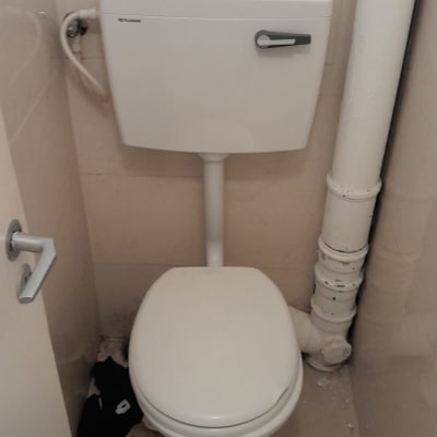 אסלה עם צינור מים לבן וקיר קרמיקה