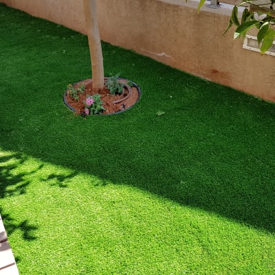 דשא סינתטי עם עץ ופרחים בגינה קטנה