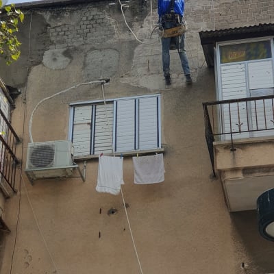 אדם על חבל מבצע עבודת איטום על קיר בניין