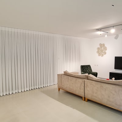 וילון לבן ארוך תלוי על קיר בחדר מגורים