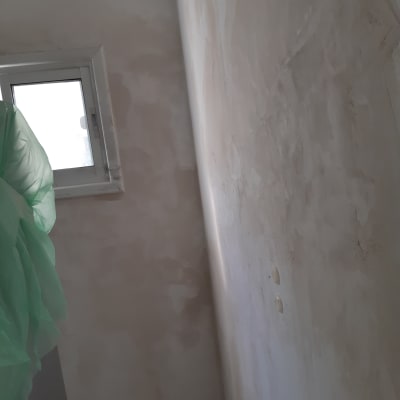 קיר מטויח עם חלון קטן ויריעה ירוקה