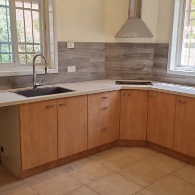 מטבח עם ארונות עץ, כיור וברז, קירות מחופים