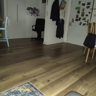 רצפת פרקט עץ כהה עם שטיח צבעוני בפינה