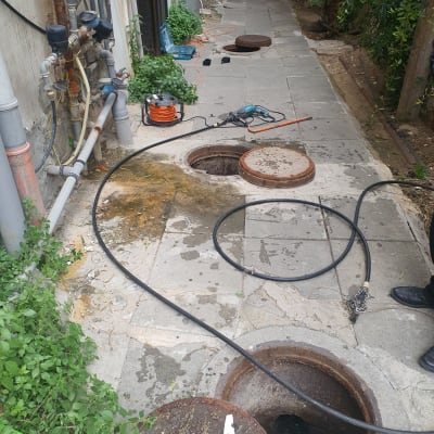 צינורות וכלי עבודה ליד פתח ביוב פתוח