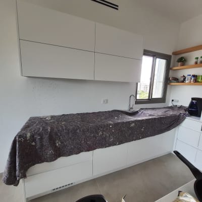 מטבח עם ארונות מכוסים בבד כהה, כיור חשוף