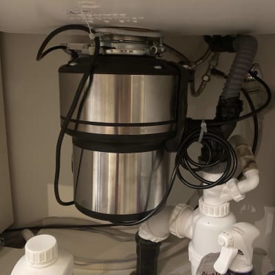 מכשיר טוחן אשפה מתחת לכיור עם צינורות חיבור