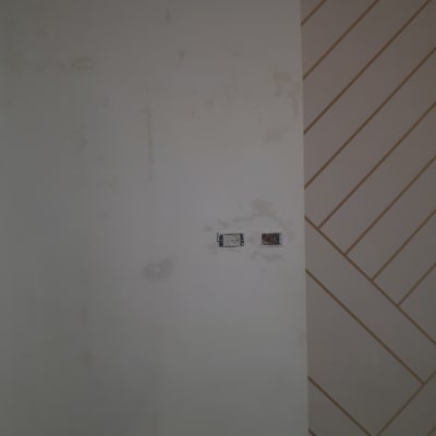 קיר צבוע חלקית עם סימני שפכטל ושקע חשמל