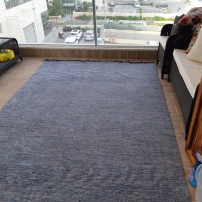 שטיח כחול על רצפת מרפסת עם ספה וכריות