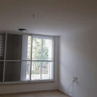 קיר לבן עם חלון גדול ותריסים