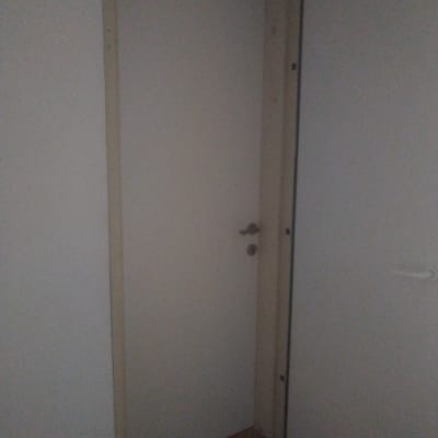 דלת לבנה עם ידית מתכת במסגרת עץ