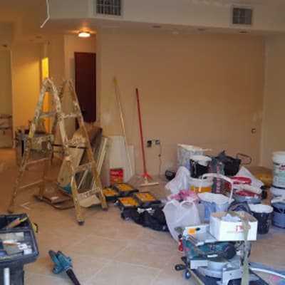 חדר בשיפוץ עם סולם, דליים וכלי עבודה על הרצפה