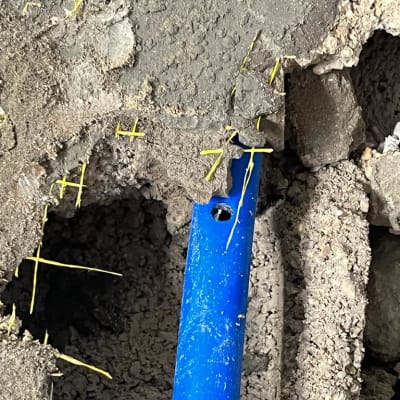 צינור כחול בקיר בטון עם חור