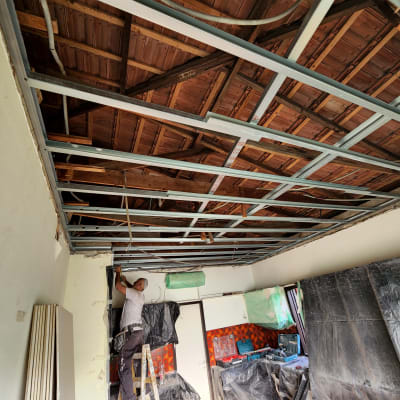 עובד מתקין תקרת גבס עם שלד מתכת