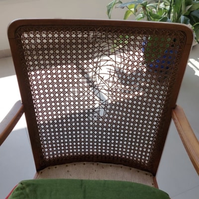 כרית ירוקה על כיסא עם משענת קש שבורה