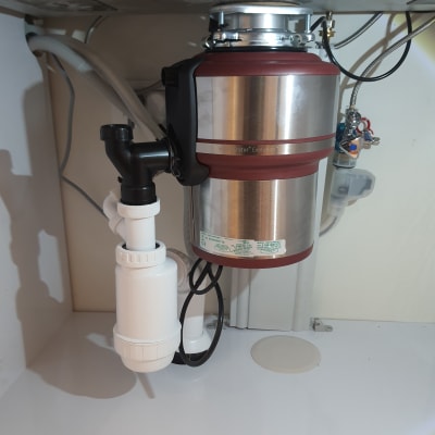 מכשיר טוחן אשפה מתחת לכיור עם צינורות חיבור