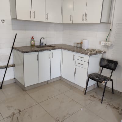 מטבח עם ארונות לבנים, בקבוק חומר ניקוי על השיש