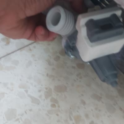 יד מחזיקה חלק פלסטיק אפור ולבן על רצפה