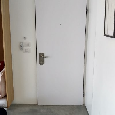 דלת לבנה עם ידית מתכת על רצפת בטון