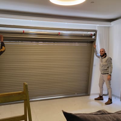 שני אנשים מתקינים תריס אלומיניום בחדר