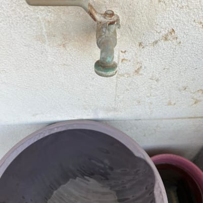 ברז חלוד על קיר עם דלי מים מתחת