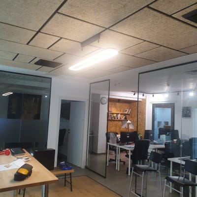 מנורת תקרה מוארת במשרד עם שולחנות וכיסאות