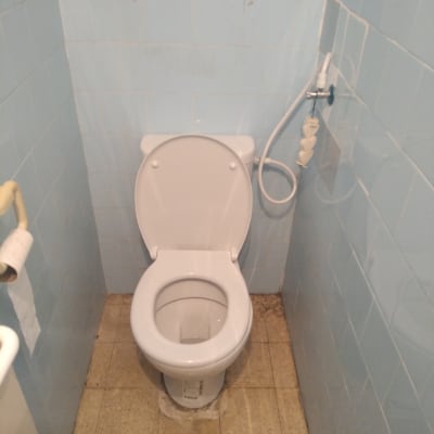 אסלה עם מושב פתוח וצינור מים ליד