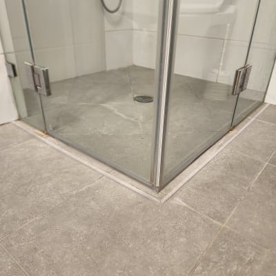 מקלחון זכוכית עם רצפת אריחים אפורה