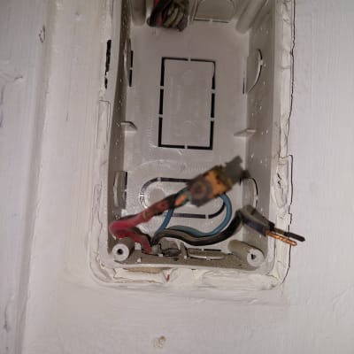 חוטי חשמל חשופים בתיבת חיבורים בקיר