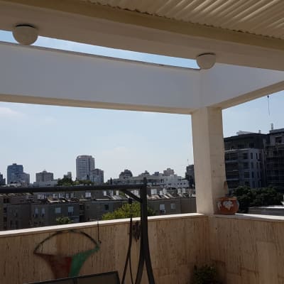 מרפסת עם קירות אבן, עציצים ומנורה תלויה