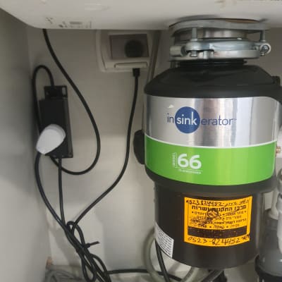 מכשיר טוחן אשפה מתחת לכיור עם חיבורים חשמליים