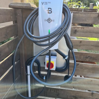 מטען חשמלי לרכב עם כבל תלוי על קיר עץ