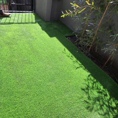 דשא סינתטי עם צמחייה ירוקה ליד גדר