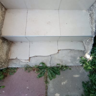 מדרגות שבורות עם אריחים סדוקים ועשבים