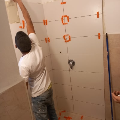 אדם מתקין אריחים עם פלסטרים כתומים על קיר