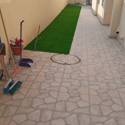 כלי גינון ליד דשא מלאכותי בשביל מרוצף