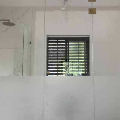 דלת זכוכית עם צירים מוזהבים בחדר רחצה